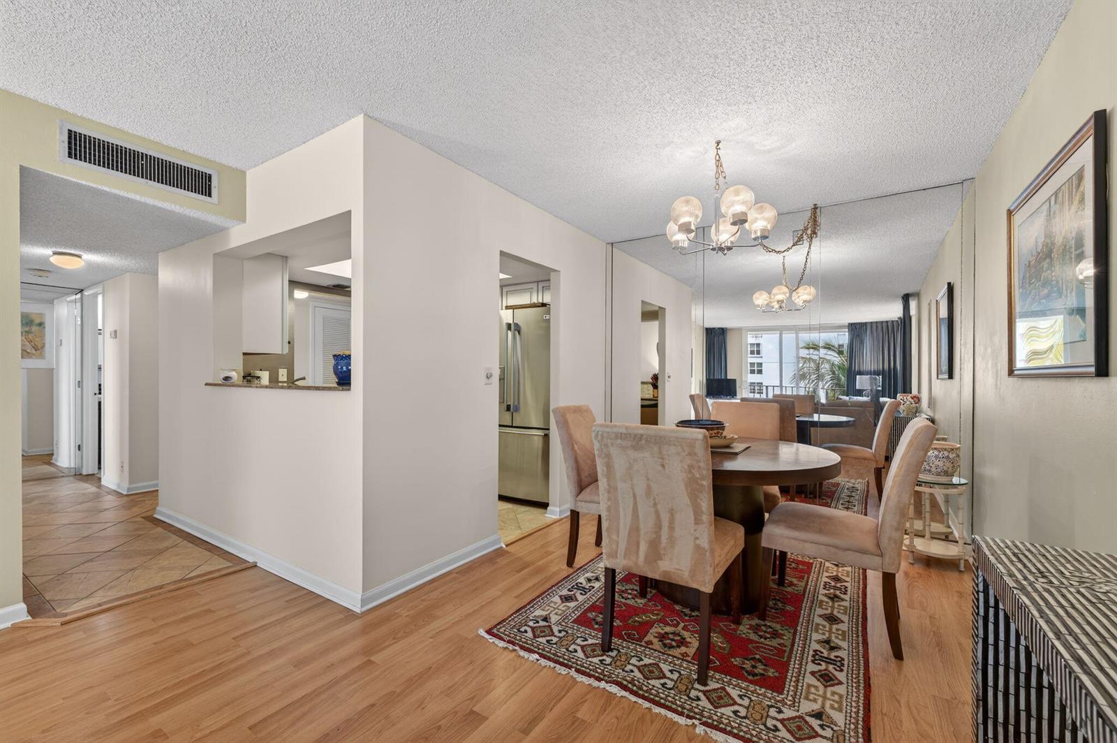 A dining area with a round table, upholstered chairs, and a red patterned area rug — 1009 N Ocean Boulevard # 312, Pompano Beach FL 33062, POMPANO BEACH, FL