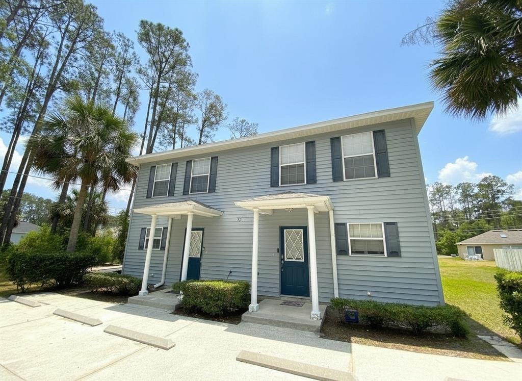 A two-story duplex with light blue siding, dark shutters, and two covered front entrances — 23 REGENT LANE UNIT A&B, PALM COAST, FL