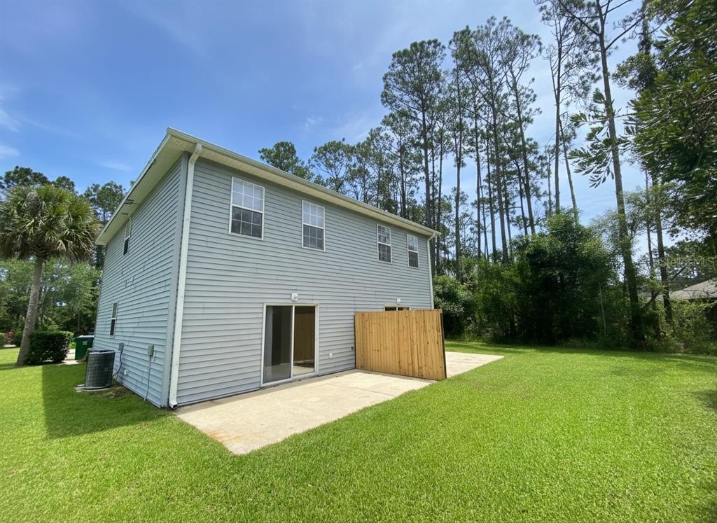 The exterior of a two-story house features gray siding, a concrete patio, and a wooden fence — 23 REGENT LANE UNIT A&B, PALM COAST, FL