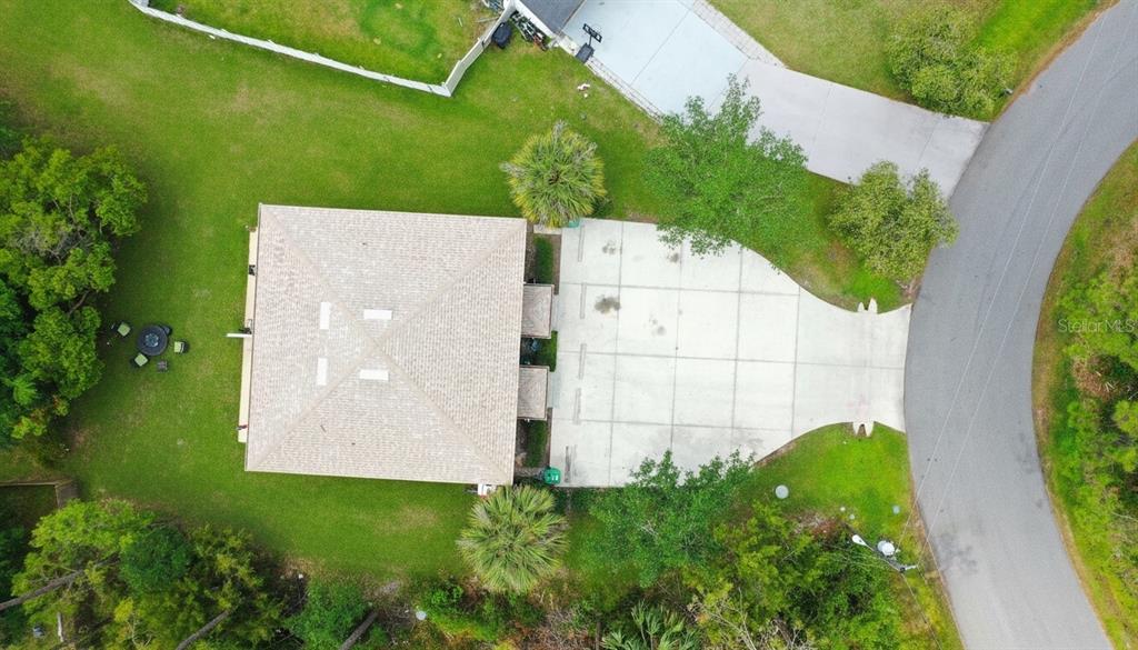An aerial view shows a house with a large concrete driveway and surrounding green lawn — 23 REGENT LANE UNIT A&B, PALM COAST, FL