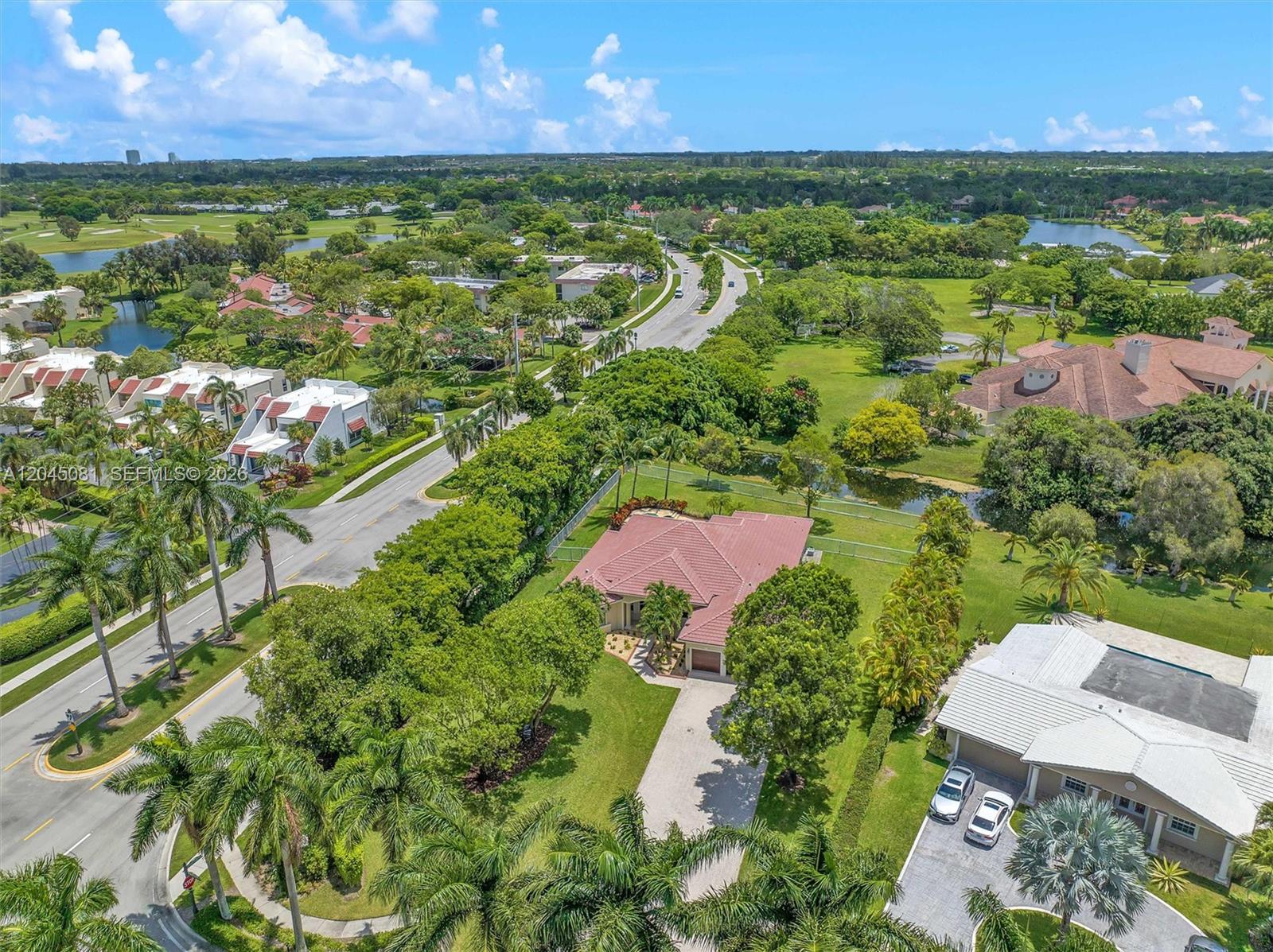 An aerial view shows a residential neighborhood with a house featuring a red-tiled roof — 16310 Paddock Ln, Weston FL 33326, WESTON, FL