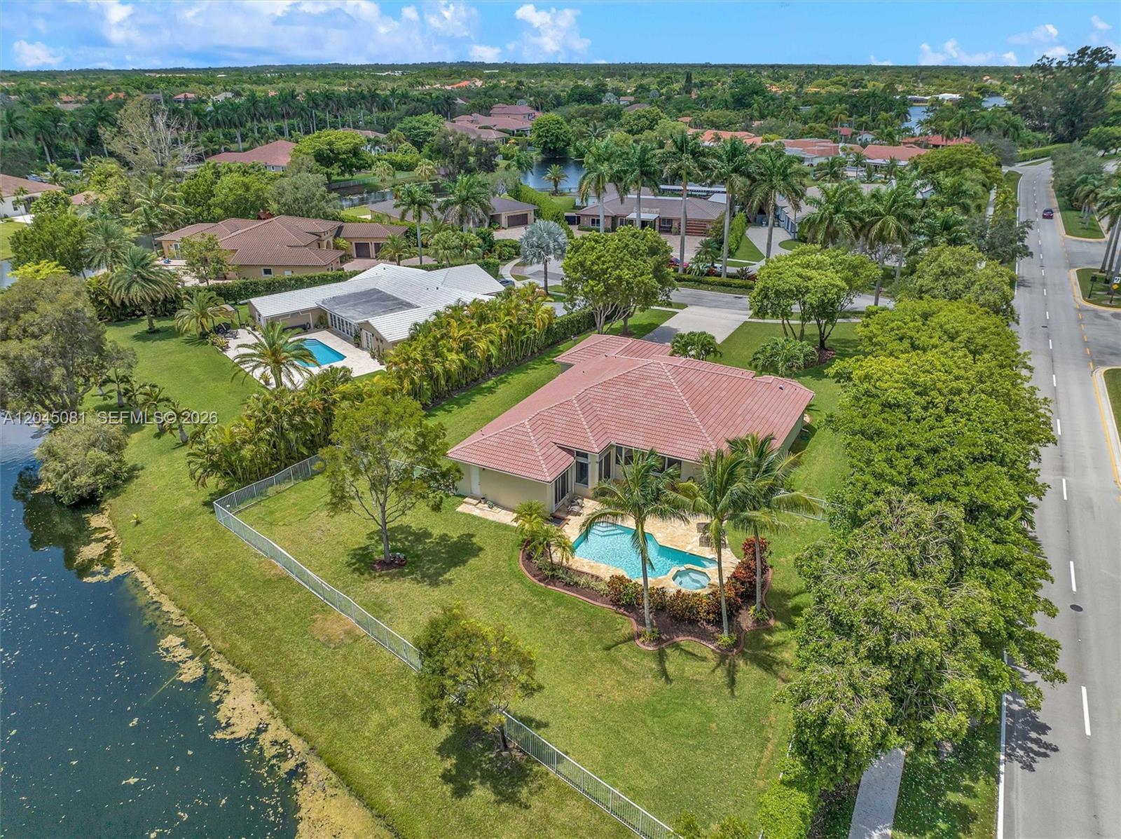 An aerial view shows a house with a red tile roof, pool, and backyard lake — 16310 Paddock Ln, Weston FL 33326, WESTON, FL
