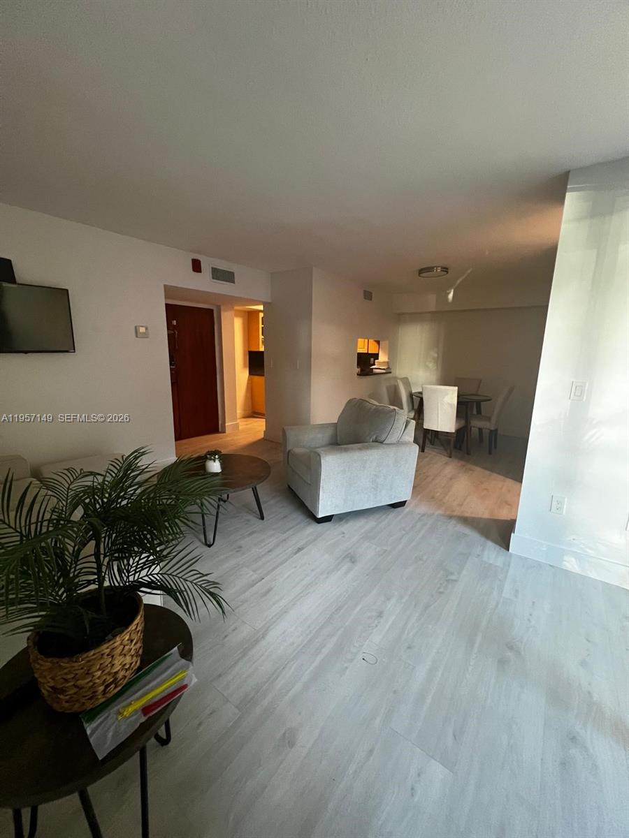 A living room with light wood-look flooring leads to a dining area and kitchen — 11750 SW 18th St # 1, Miami FL 33175, MIAMI, FL