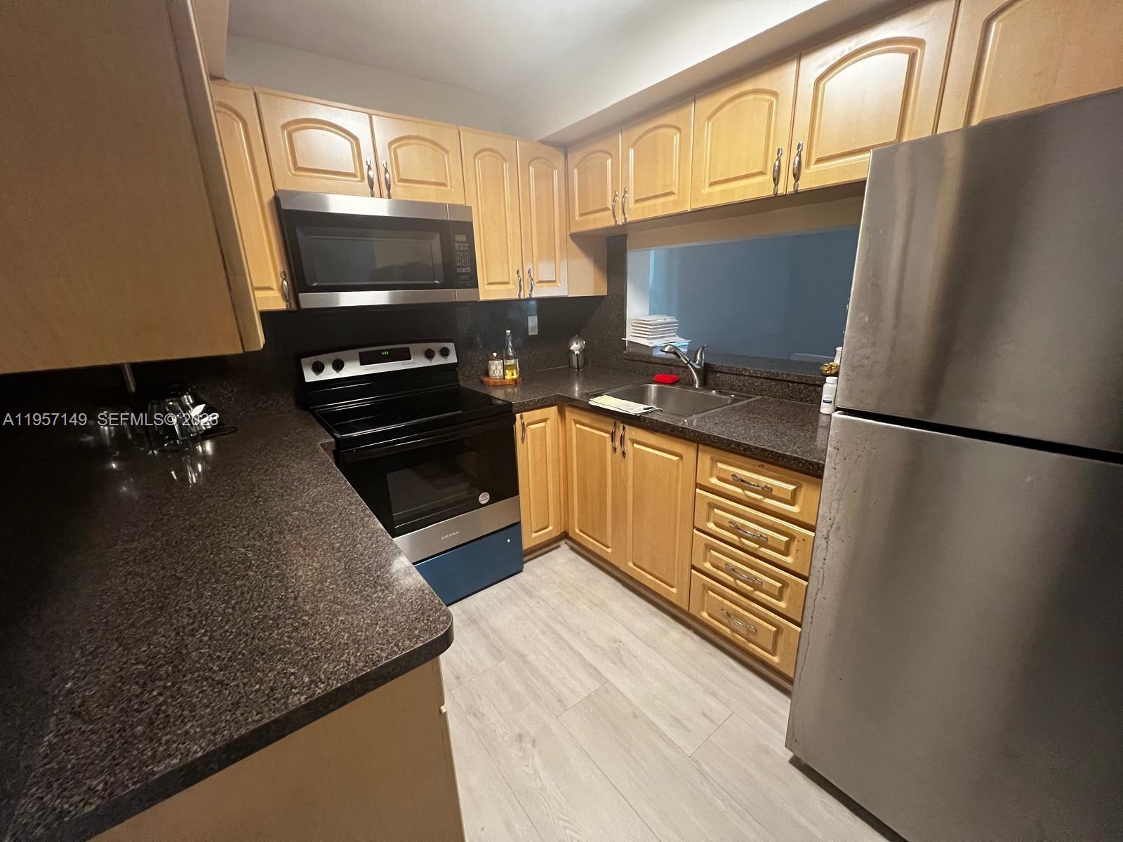 A kitchen features light wood cabinets, dark granite countertops, and stainless steel appliances — 11750 SW 18th St # 1, Miami FL 33175, MIAMI, FL