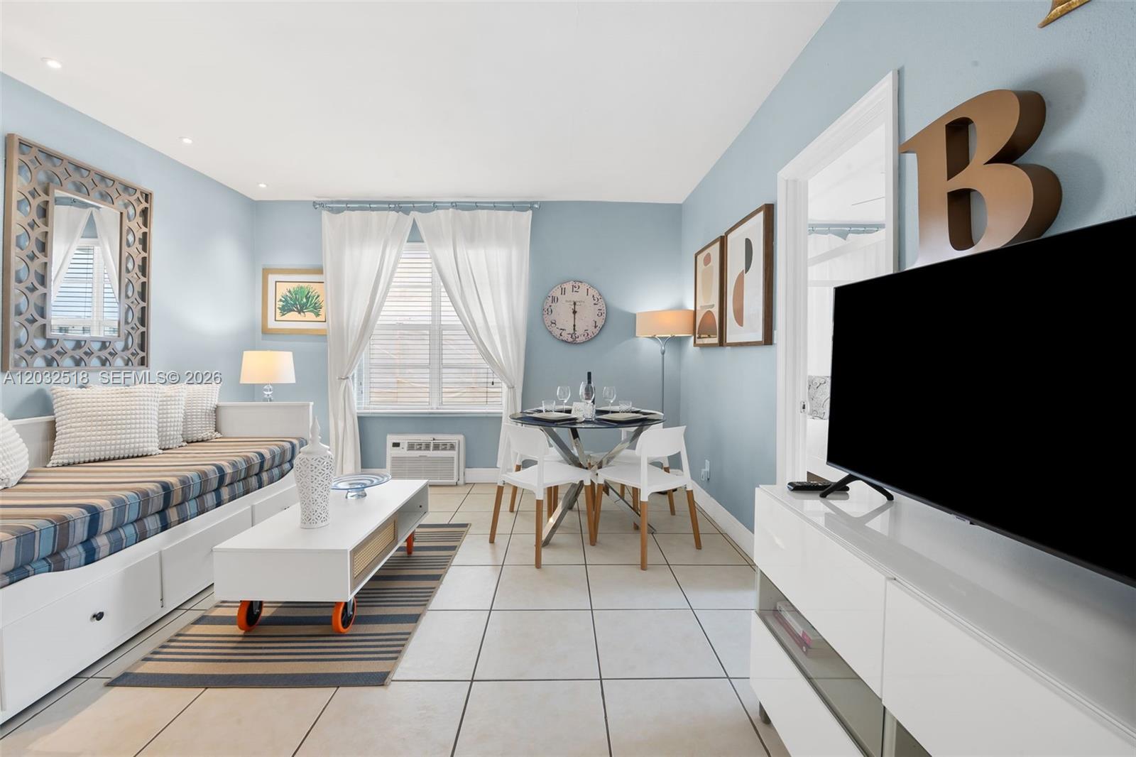 A living and dining area features light blue walls, tiled floors, and a daybed — 3030 Collins Ave # 4E, Miami Beach FL 33140, MIAMI BEACH, FL