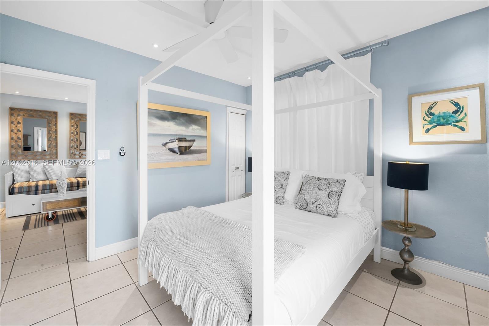 A bedroom features a white canopy bed, light blue walls, and tile flooring — 3030 Collins Ave # 4E, Miami Beach FL 33140, MIAMI BEACH, FL