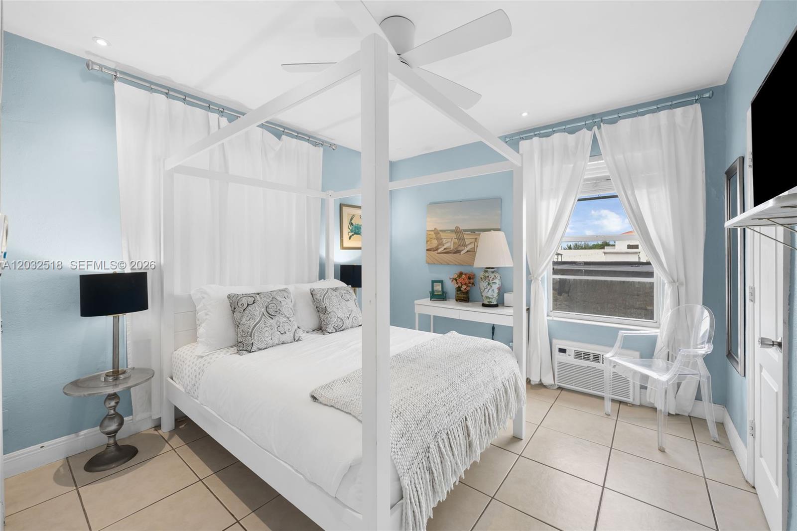 A bedroom features a white canopy bed, light blue walls, tile flooring, and a window — 3030 Collins Ave # 4E, Miami Beach FL 33140, MIAMI BEACH, FL