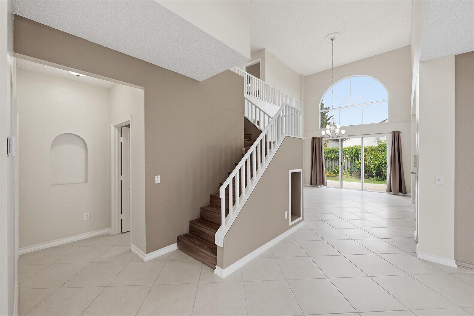 An entryway with tile floors leads to a staircase and a bright living area beyond — 18474 Old Princeton Lane, Boca Raton FL 33498, BOCA RATON, FL