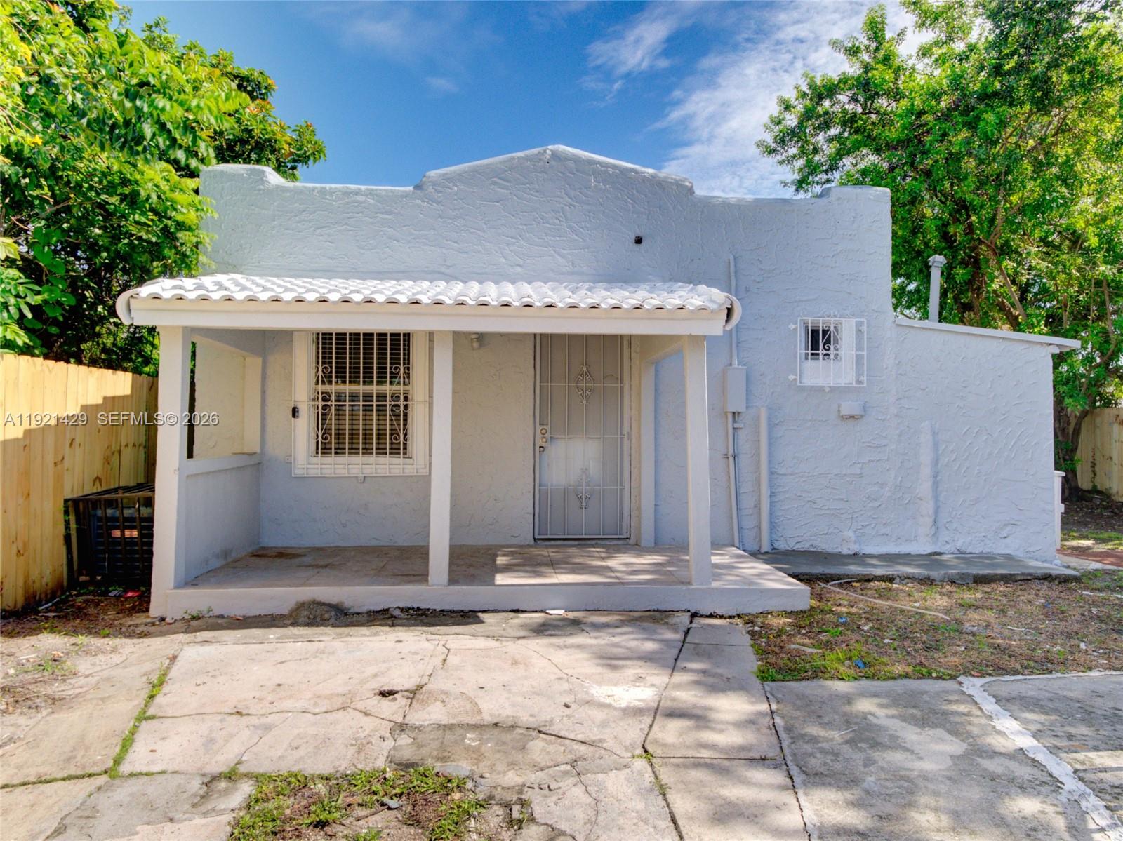 A light blue, single-story house features a front porch with a white tiled roof — 1845 NW 55th St, Miami FL 33142, MIAMI, FL