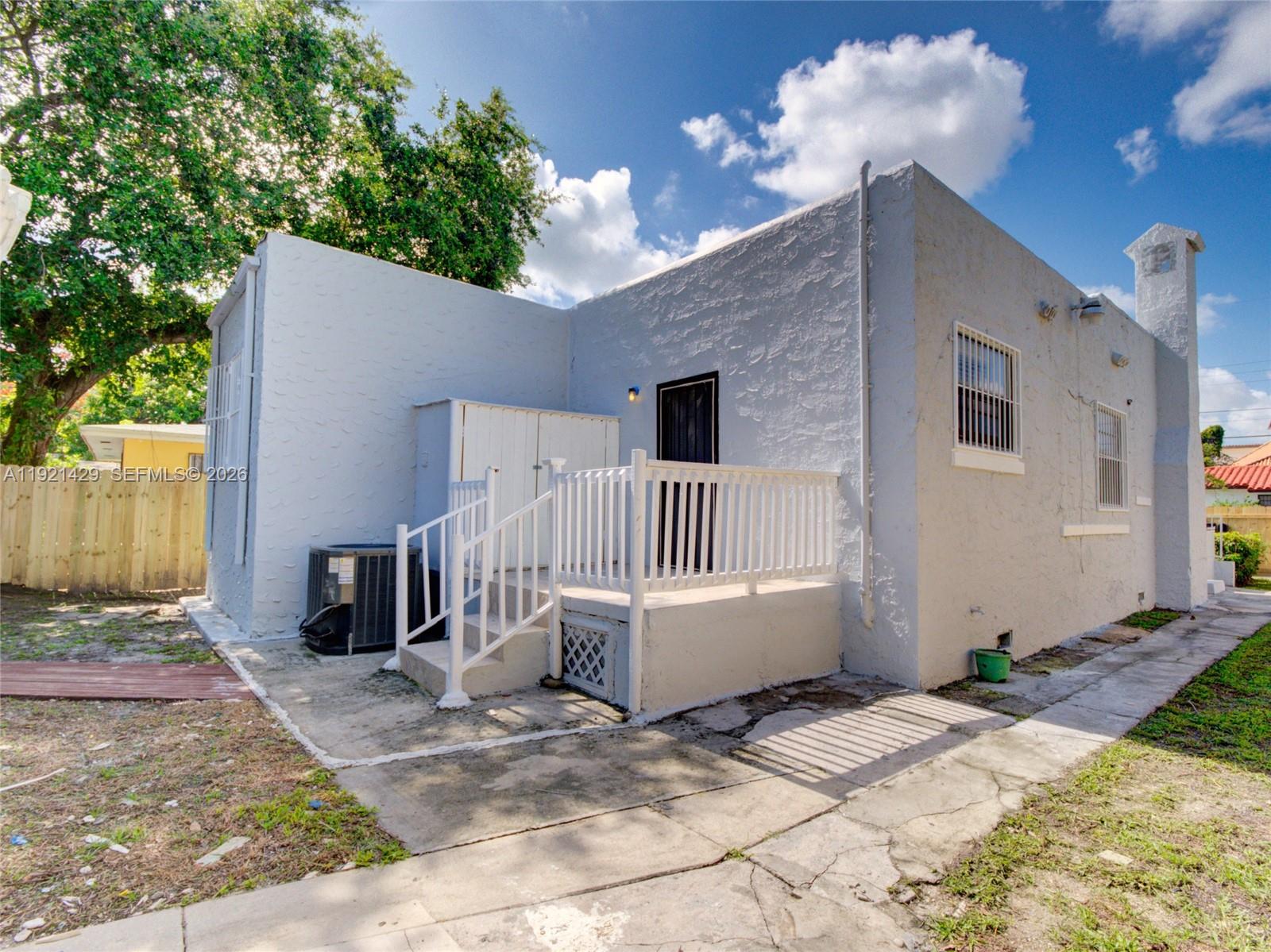 The exterior of a light blue stucco house features a small deck and a chimney — 1845 NW 55th St, Miami FL 33142, MIAMI, FL