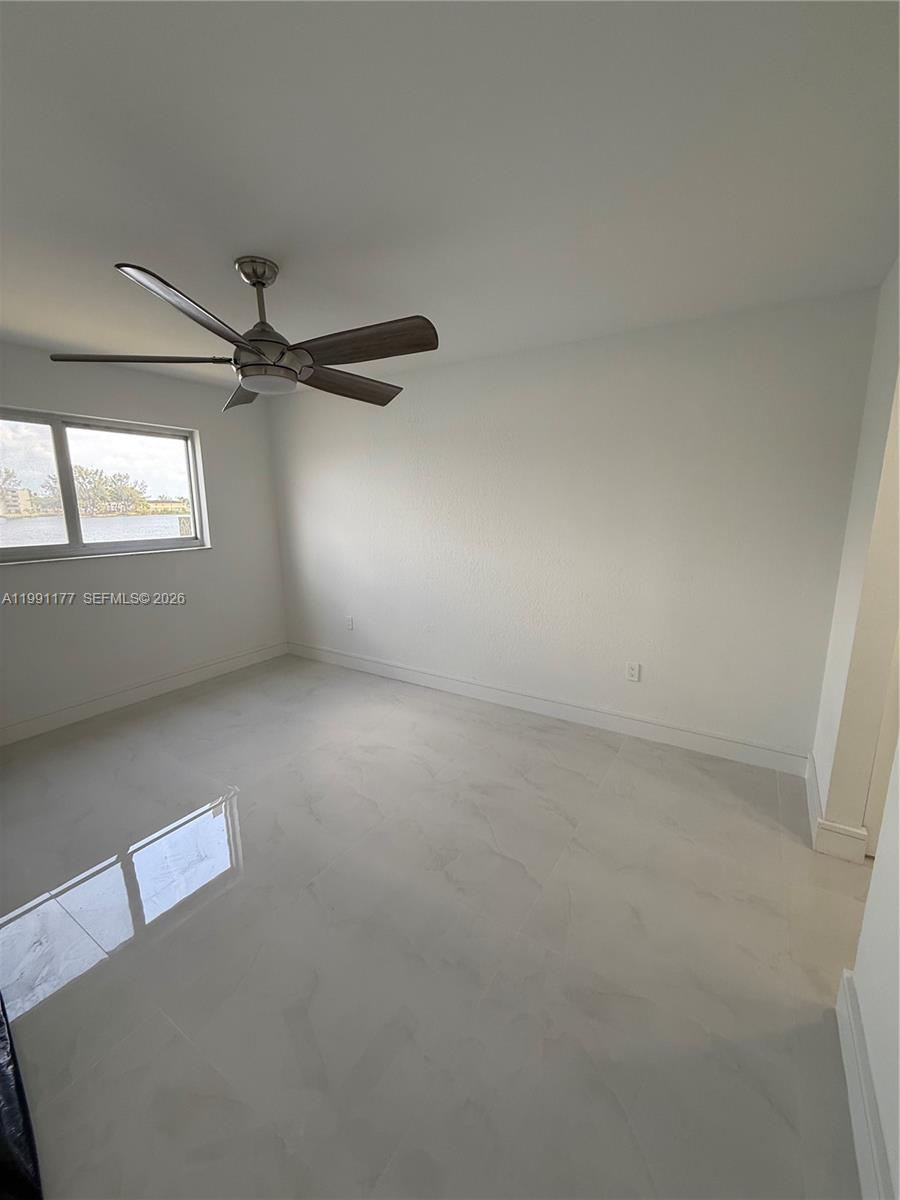 An empty bedroom features white walls, light-colored tile flooring, and a ceiling fan — 9915 W Okeechobee Rd # 201, Hialeah Gardens FL 33016, HIALEAH GARDENS, FL