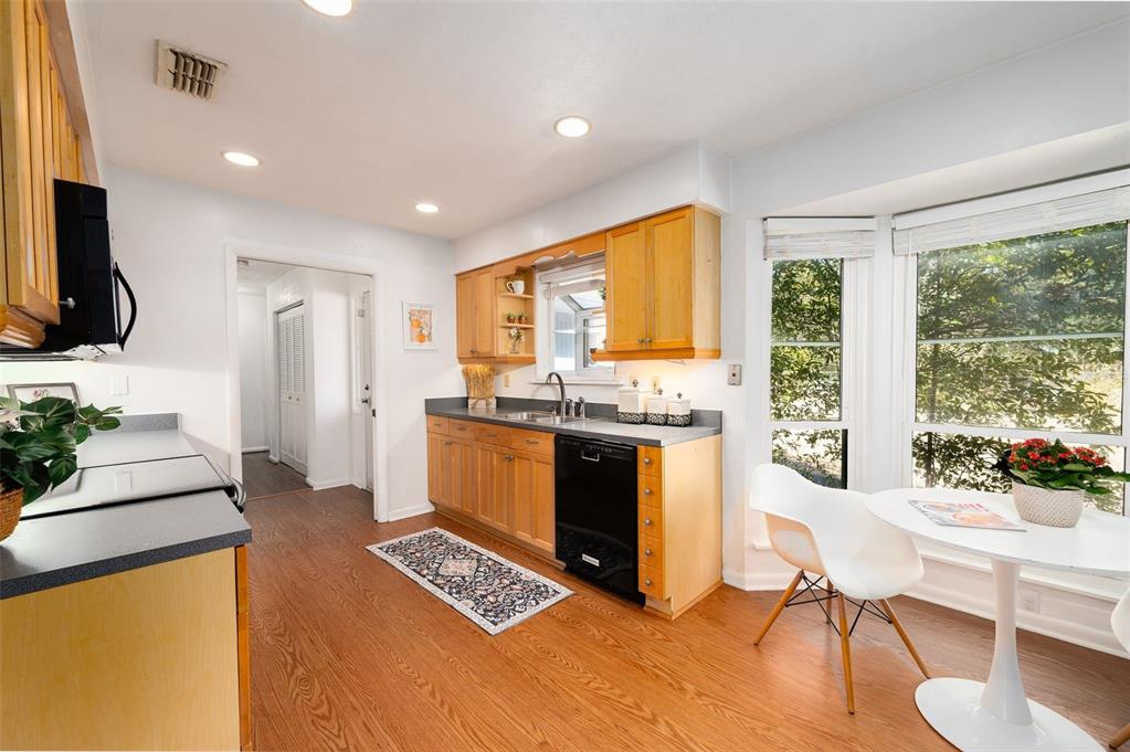 A kitchen features light wood cabinets, dark countertops, a black dishwasher, and a breakfast nook — 7220 SW 75TH STREET, GAINESVILLE, FL