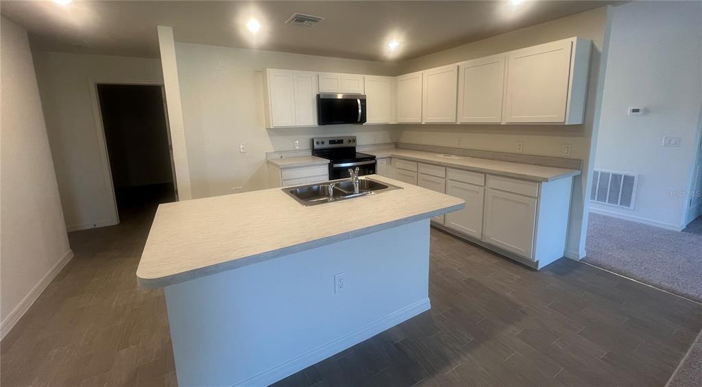 A kitchen with white cabinets, a central island with a sink, and light-colored countertops — 1436 PULASKI STREET, PORT CHARLOTTE, FL
