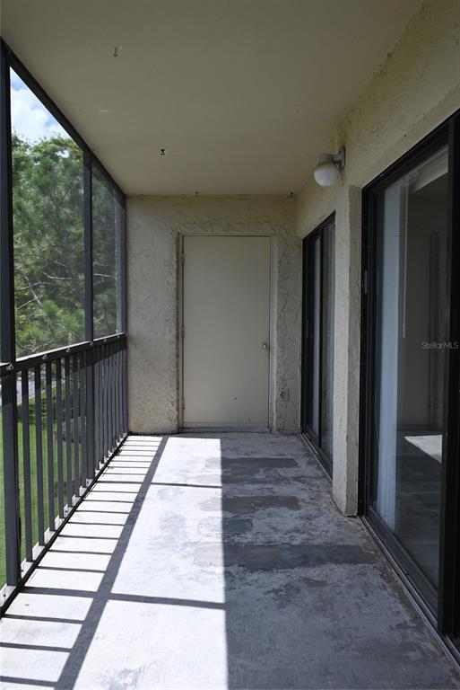 A screened-in balcony features a concrete floor, a utility door, and sliding glass doors — 2700 COVE CAY DRIVE UNIT 1-4G, CLEARWATER, FL