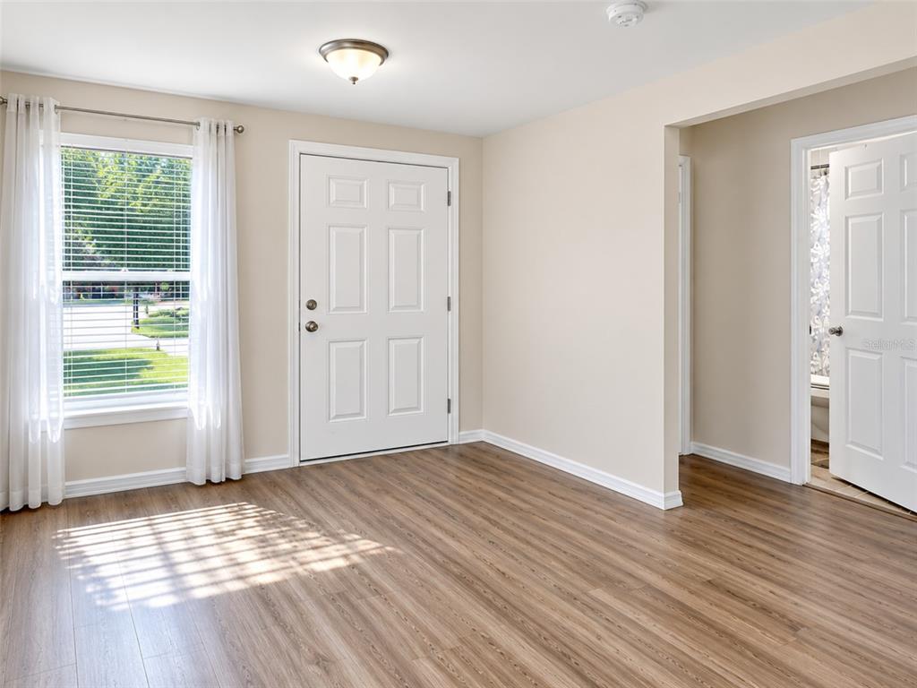 An interior view of an entryway with light wood-look flooring, a white door, and windows — 1938 LILLIE STREET, FORT MYERS, FL