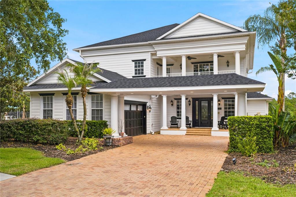 A two-story white house features a brick driveway, a covered entryway, and a balcony — 7481 GATHERING LOOP, REUNION, FL