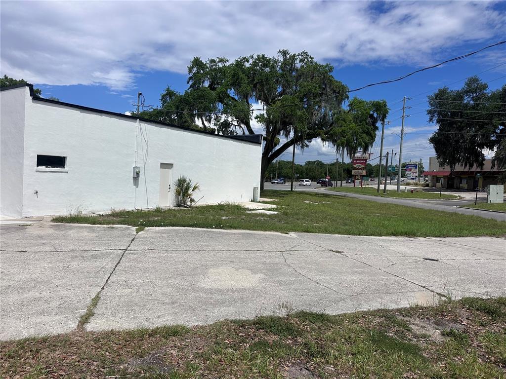 A white building stands beside a paved lot and a large tree under a blue sky — US hwy 41 E GRACE STREET STREET E, INVERNESS, FL
