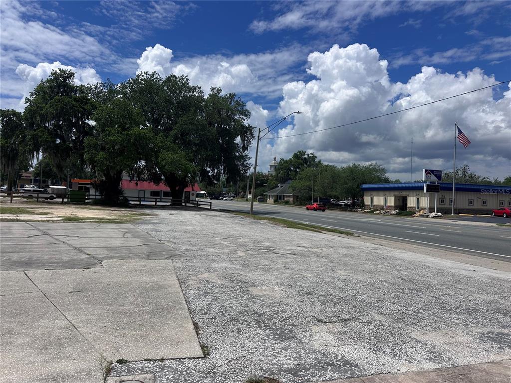 A vacant paved lot sits beside a road with trees and buildings in the background — US hwy 41 E GRACE STREET STREET E, INVERNESS, FL