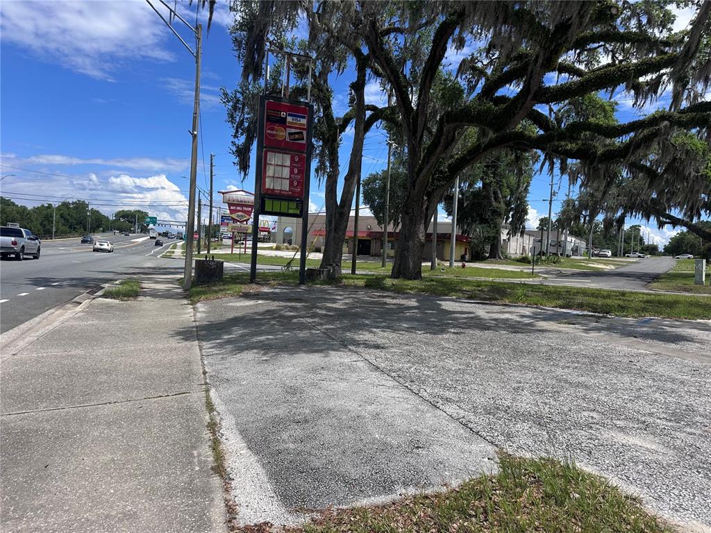 A paved lot sits beside a sidewalk and a tall gas station price sign — US hwy 41 E GRACE STREET STREET E, INVERNESS, FL