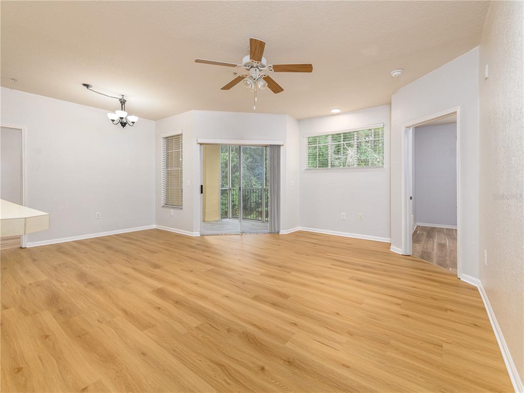 A spacious living area features light wood-look flooring, a ceiling fan, and sliding glass doors — 5125 PALM SPRINGS BOULEVARD UNIT 2206, TAMPA, FL