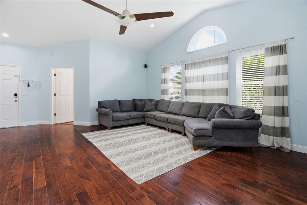 A living room features a grey sectional sofa, a patterned area rug, and hardwood floors — 12118 DICKENSON LANE, ORLANDO, FL