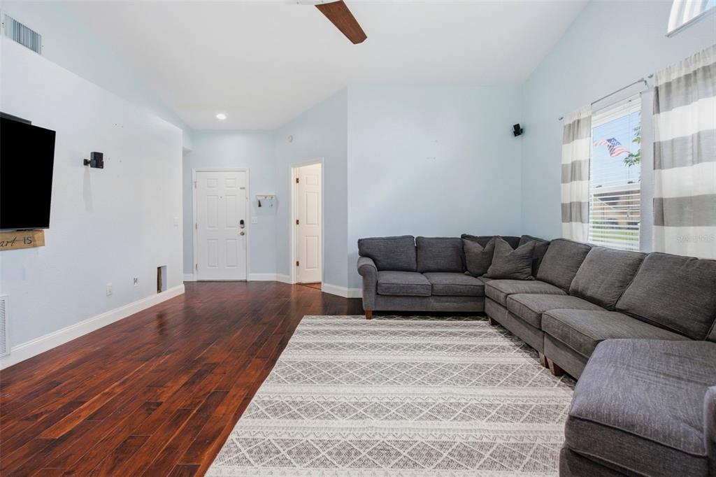 A living room features dark wood flooring, light blue walls, and a large gray sectional sofa — 12118 DICKENSON LANE, ORLANDO, FL