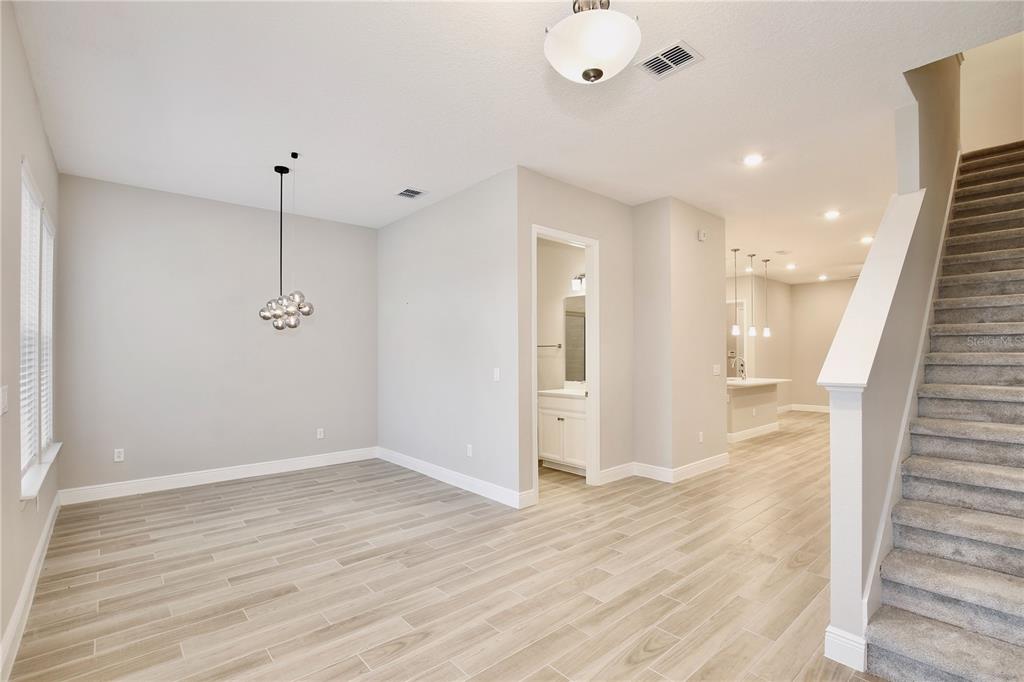 An interior view shows a dining area with wood-look tile floors, a pendant light, and stairs — 6491 CYRILS DRIVE, ST CLOUD, FL
