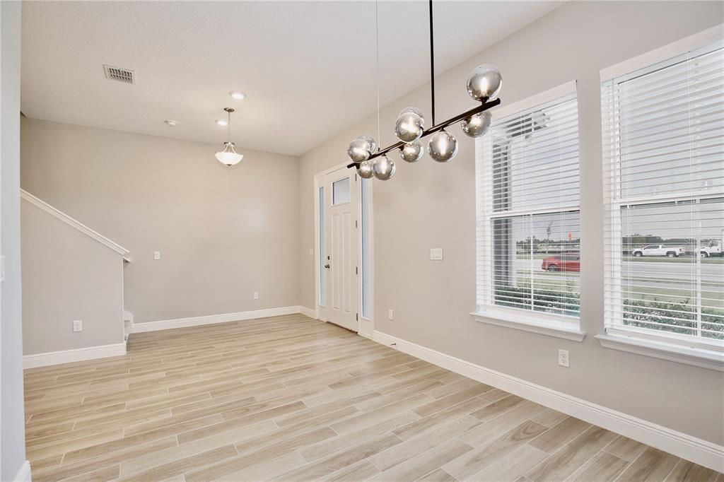 A dining area features light wood-look tile flooring, a modern globe chandelier, and two windows — 6491 CYRILS DRIVE, ST CLOUD, FL