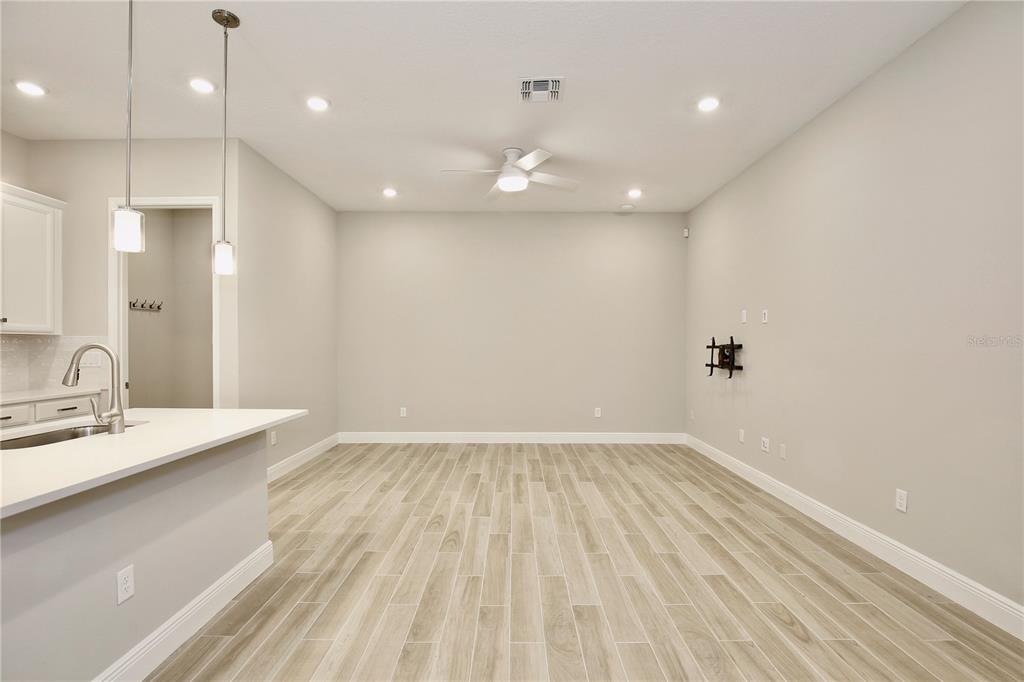 A bright, open-concept living area features light wood-look tile flooring and a ceiling fan — 6491 CYRILS DRIVE, ST CLOUD, FL