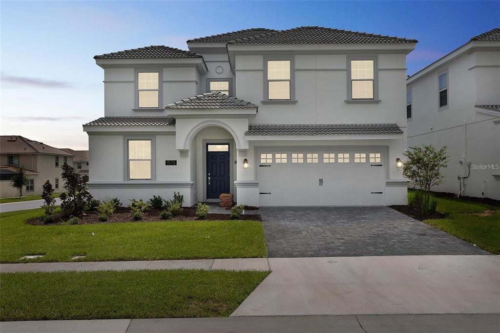 A two-story white house with a tiled roof, dark blue front door, and paved driveway — 1575 PLUNKER DRIVE, DAVENPORT, FL