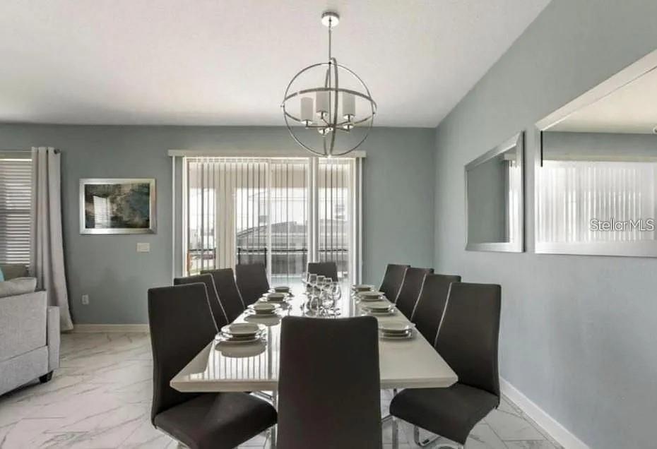 A dining room features a white table, dark chairs, a spherical chandelier, and light walls — 1575 PLUNKER DRIVE, DAVENPORT, FL
