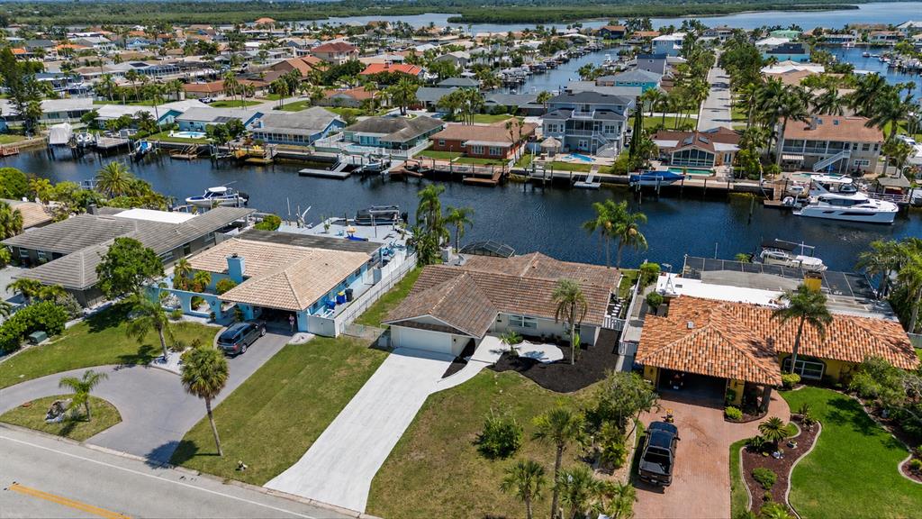 An aerial view shows three waterfront houses with driveways and boat docks along a canal — 3340 FLORAMAR TERRACE, NEW PORT RICHEY, FL