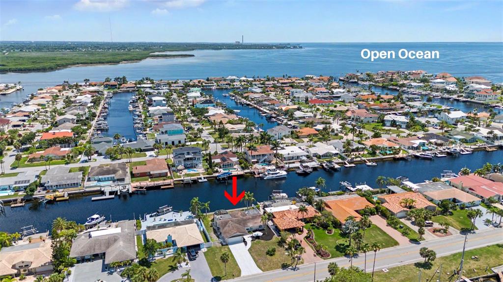 An aerial view shows a waterfront house with a red arrow pointing toward its backyard — 3340 FLORAMAR TERRACE, NEW PORT RICHEY, FL