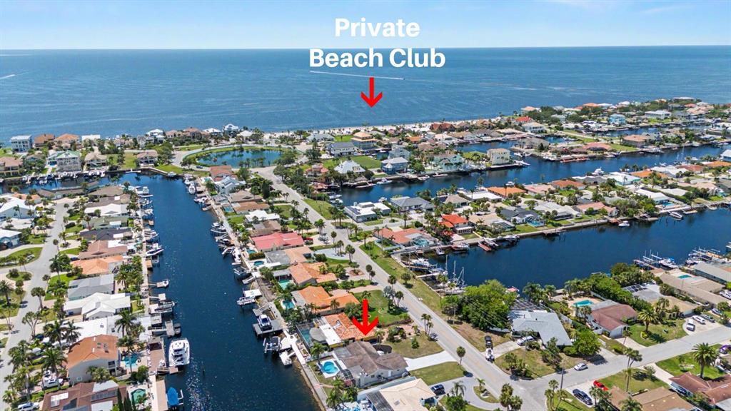 This aerial view shows a residential neighborhood with canals, boat docks, and a private beach — 3340 FLORAMAR TERRACE, NEW PORT RICHEY, FL