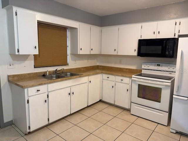 A kitchen features white cabinets, tan laminate countertops, a white stove, and tiled flooring — 2802 7TH STREET, ST CLOUD, FL