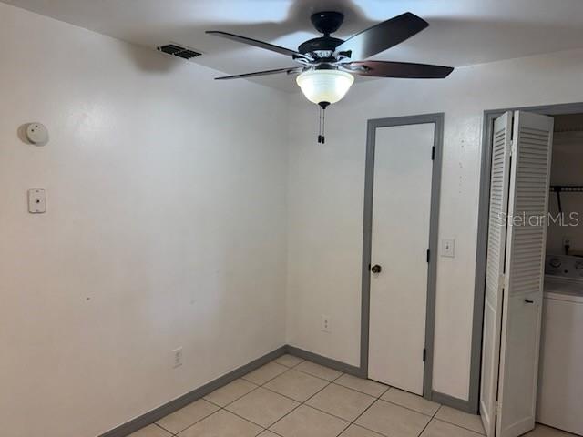 A laundry closet with white appliances sits next to a door in a tiled room — 2802 7TH STREET, ST CLOUD, FL