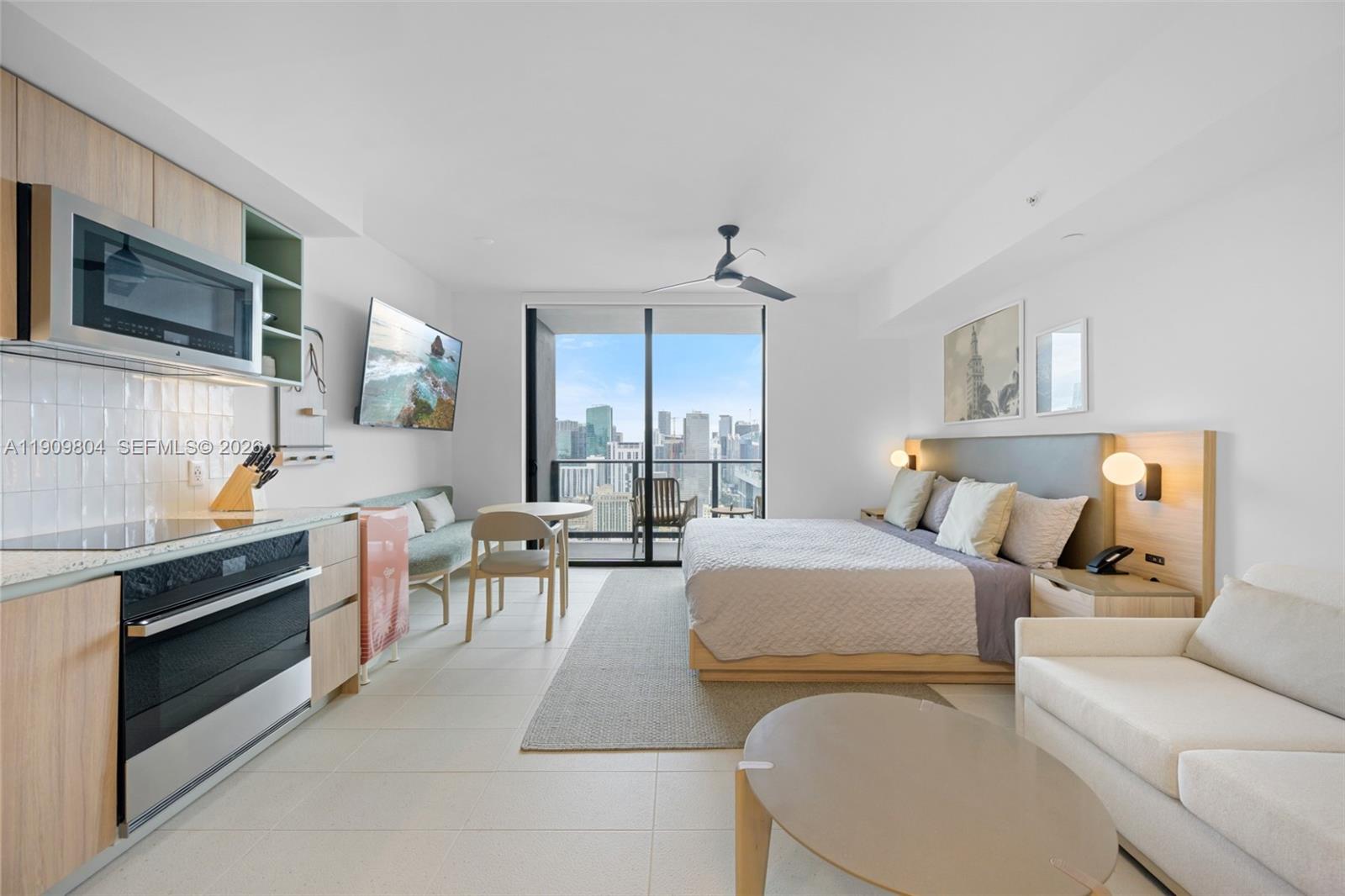 A studio apartment features a kitchen, bed, seating area, and a balcony with city views — 159 NE 6th St # 3706, Miami FL 33132, MIAMI, FL