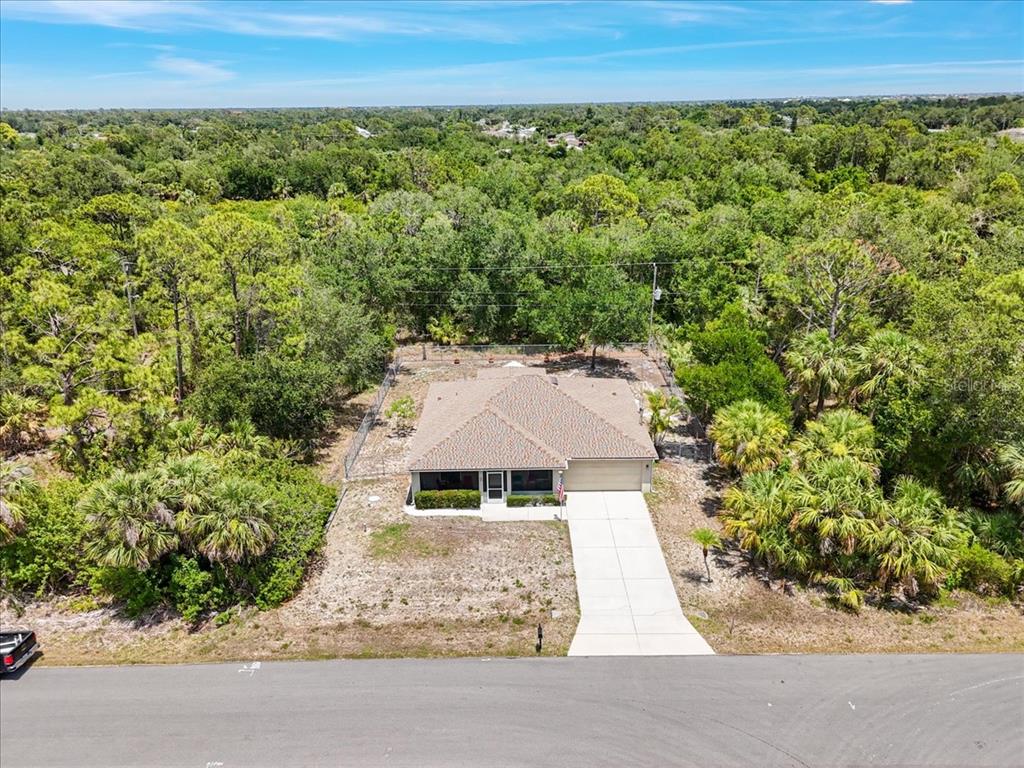 An aerial view shows a single-story house with a concrete driveway surrounded by dense trees — 3322 HAMPTON STREET, PORT CHARLOTTE, FL