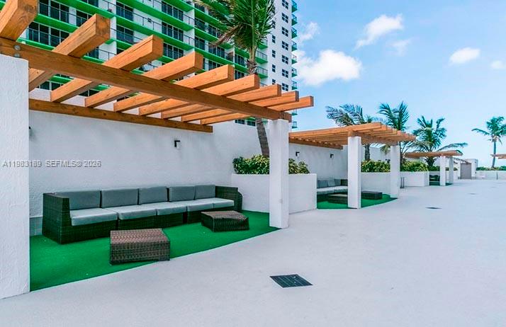 An outdoor patio features wooden pergolas over wicker lounge seating on green turf — 1750 N Bayshore Dr # 1104, Miami FL 33132, MIAMI, FL