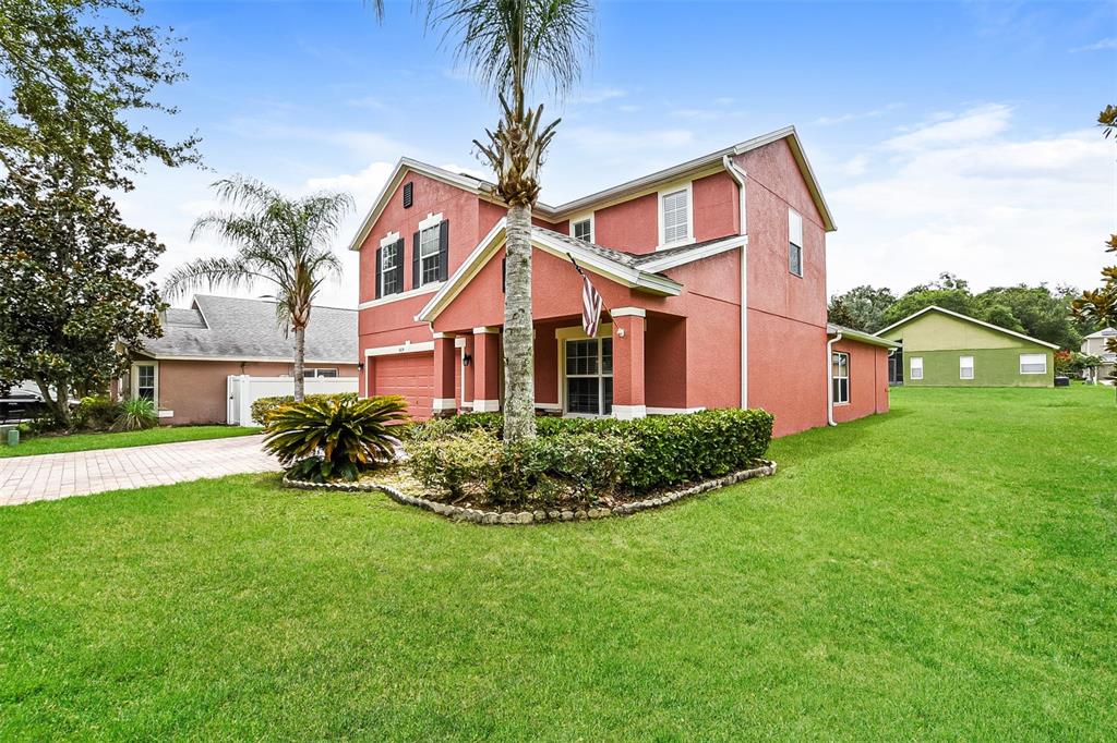 A two-story, red stucco house with a palm tree and a green lawn — 5824 GREAT EGRET DRIVE, SANFORD, FL