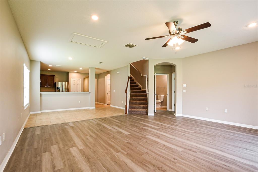 An open-concept living area features wood-look flooring, a kitchen with tile, and a carpeted staircase — 5824 GREAT EGRET DRIVE, SANFORD, FL