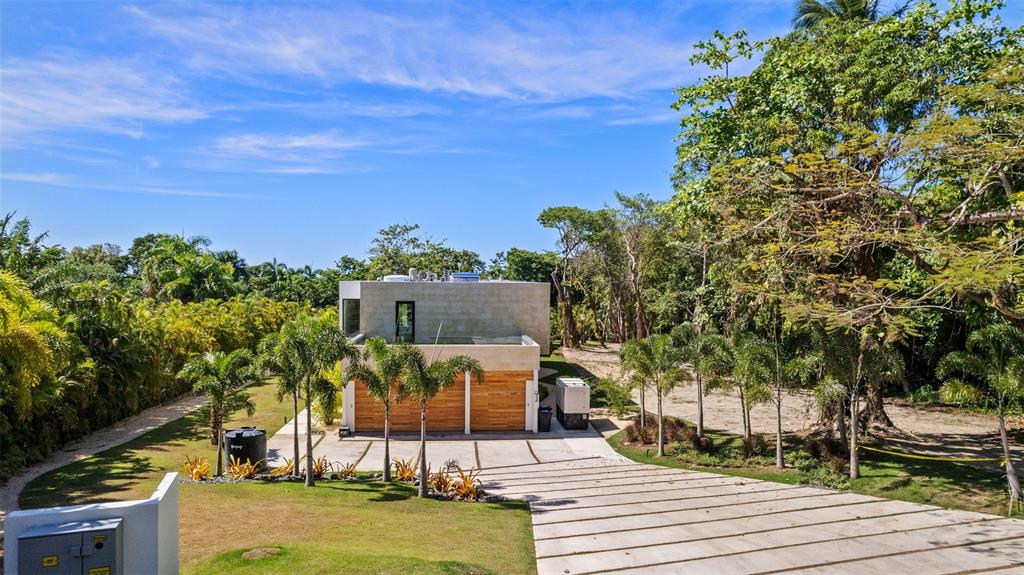 A modern two-story house with wood garage doors sits on a landscaped lot with palm trees — 904 VILLA DORADO ESTATES, DORADO, PR