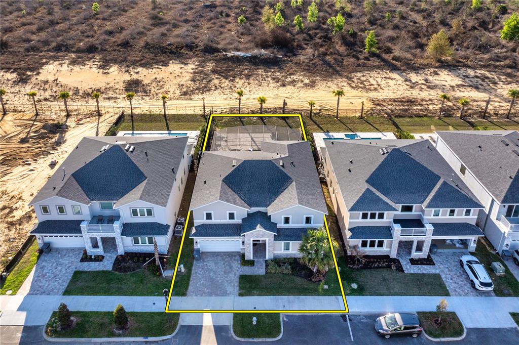 An aerial view shows a two-story house with a pool cage and paved driveway — 264 LADY ALICE DRIVE, DAVENPORT, FL