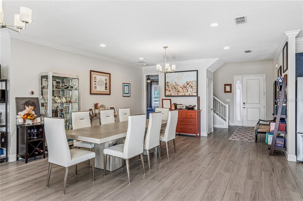 A dining room features a light wood table, white chairs, and gray wood-look flooring — 264 LADY ALICE DRIVE, DAVENPORT, FL