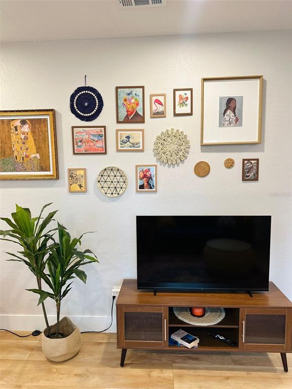 A living room features a television on a wooden console beneath a gallery wall — 6602 S FAUL STREET, TAMPA, FL