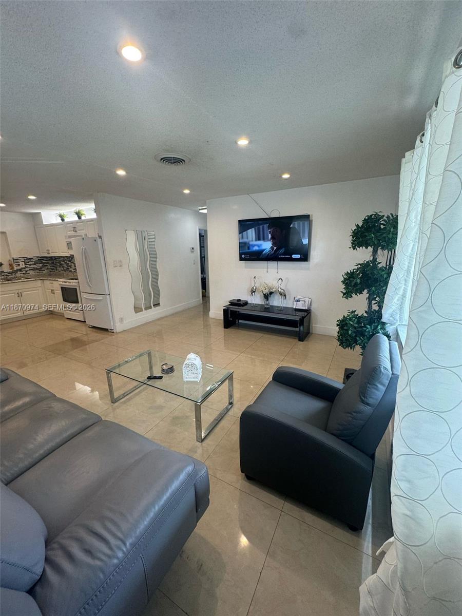 A living room with tile floors, a glass coffee table, and an adjacent open kitchen — 4808 NW 27th Ter, Tamarac FL 33309, TAMARAC, FL