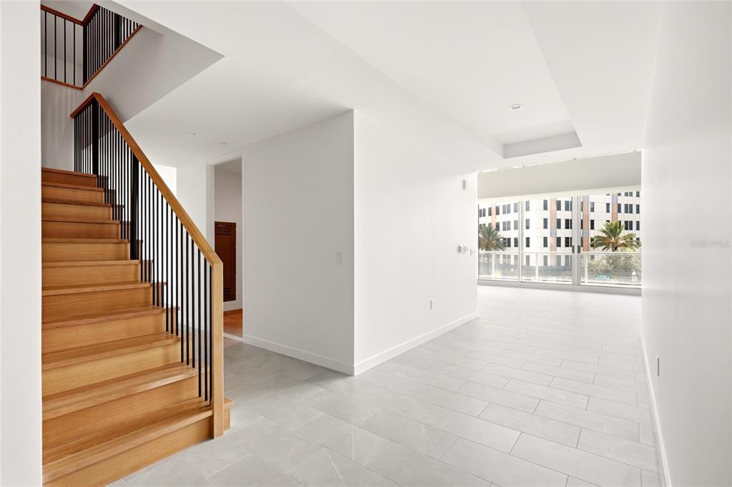 A bright, modern living room features high ceilings, floor-to-ceiling windows, and neutral-toned furniture — 400 CENTRAL AVENUE UNIT 407, ST PETERSBURG, FL