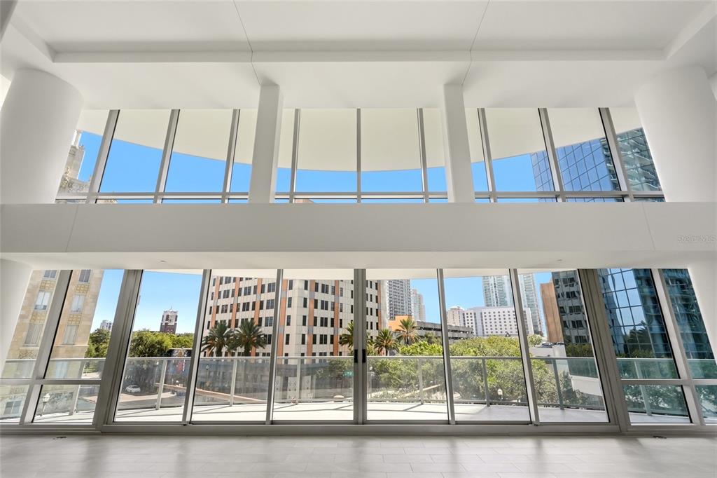 A modern bedroom features a bed, dresser, large mirror, and floor-to-ceiling windows with outdoor views — 400 CENTRAL AVENUE UNIT 407, ST PETERSBURG, FL