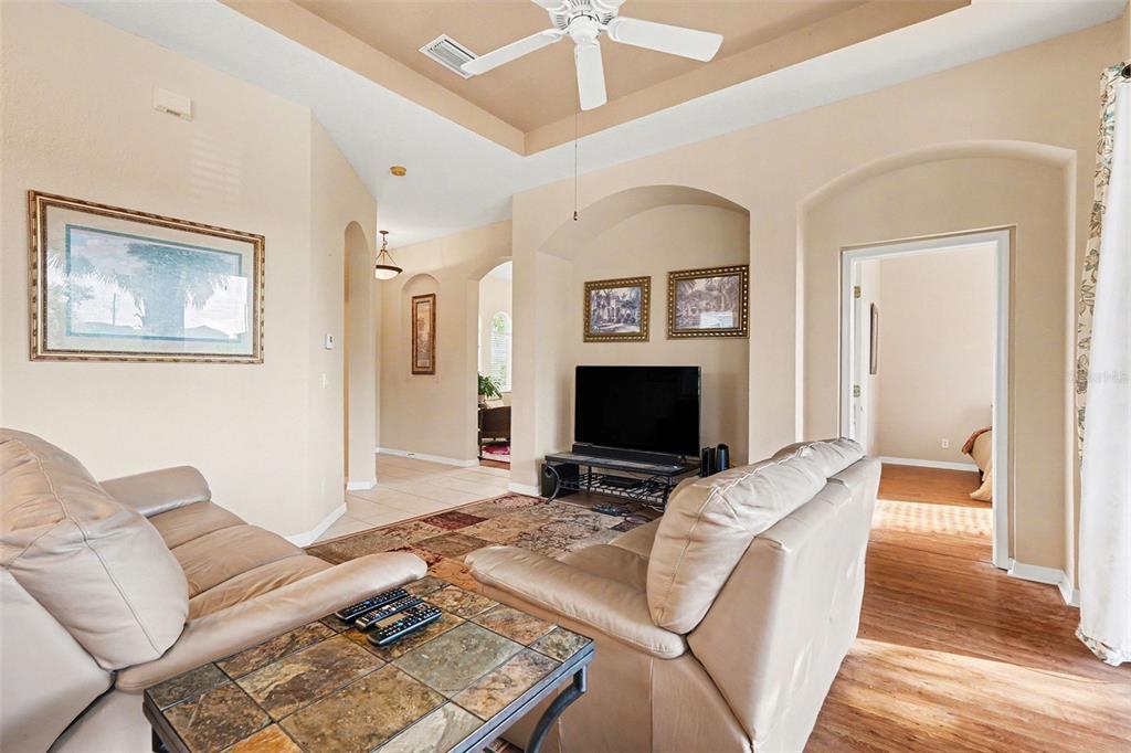 A living room features beige walls, two leather sofas, a tiled coffee table, and a television — 918 REGAL MANOR WAY, SUN CITY CENTER, FL