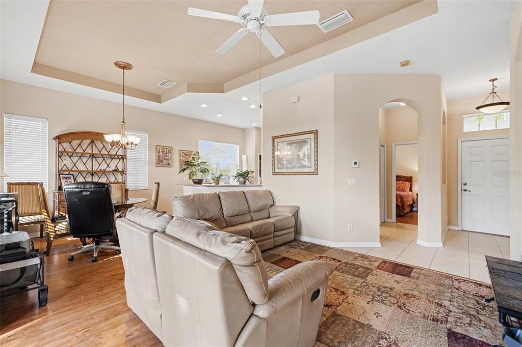 A living room with a beige leather sofa, wood floors, and a tray ceiling — 918 REGAL MANOR WAY, SUN CITY CENTER, FL